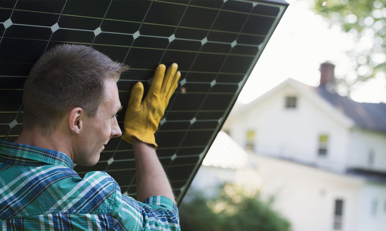 Un professionnel de l'énergie solaire qui prte un panneau solaire pour une installation sur le toit d'une maison individuelle